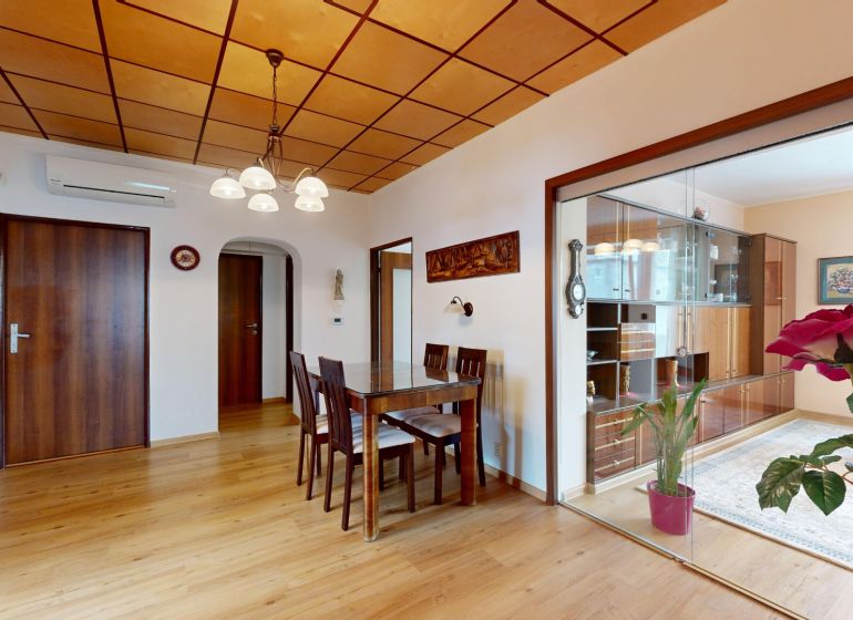 Dining table and chairs on a wooden-decor floor in a 3-room apartment.