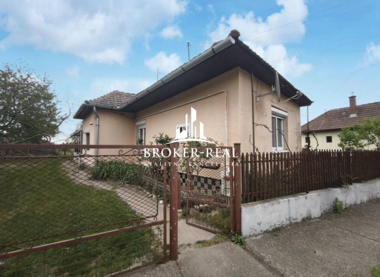 A family house in Bódvaszilas surrounded by a garden, with white plaster and a fence.