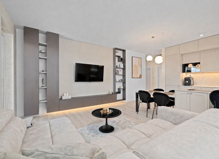 A bright living space in a 3-room apartment with a wooden decor floor and a kitchen unit.
