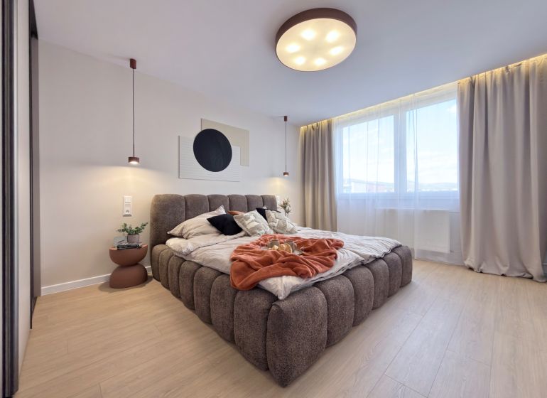 A bright bedroom with a large bed and a wooden decor floor in a 3-room apartment.