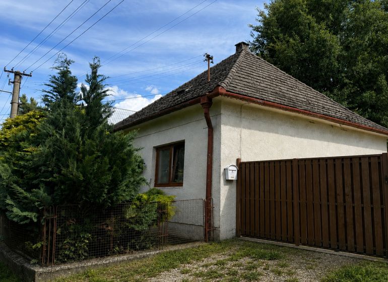 A family house in Urmince on Klačany Street, surrounded by trees and a fence.