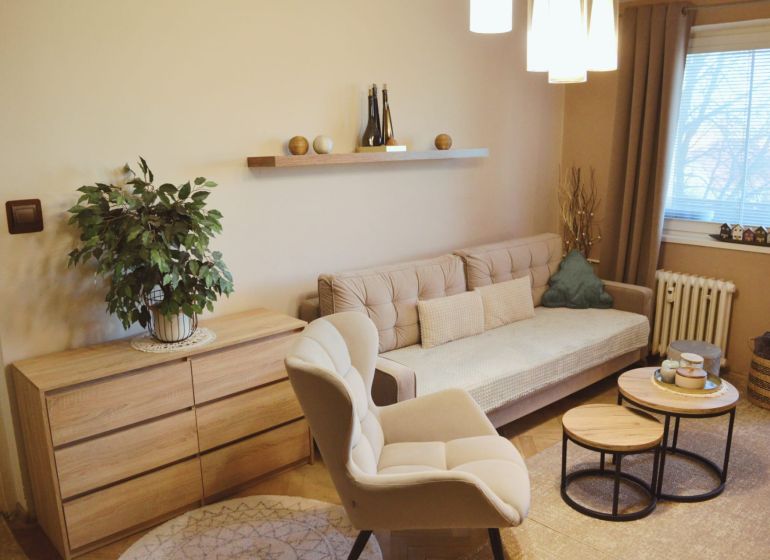 Living room of a three-room apartment with a sofa, an armchair, and a wooden decor floor.