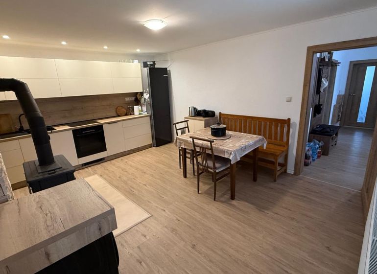 Kitchen and dining room with a fireplace, long table, wooden decor flooring, family house.