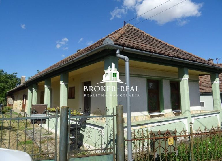 A family house in Abaujvár with a traditional roof and a green facade under a blue sky.