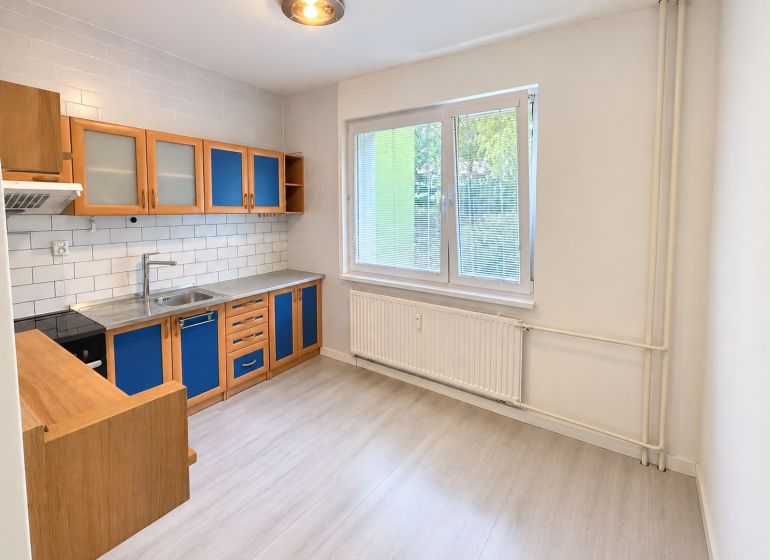 A kitchen in a 3-room apartment with blue cabinets and a wooden decor floor.