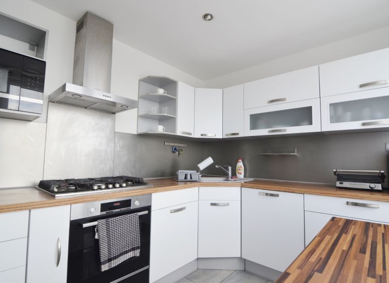 A kitchen in a 4-room apartment with white cabinets and stainless steel appliances.