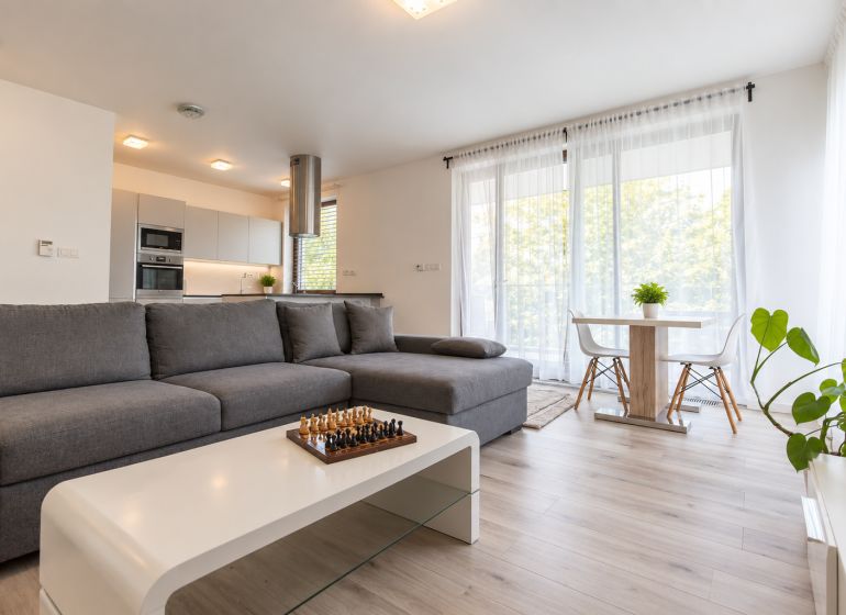 A bright living room with a kitchen, with a wooden decor floor in a 2-room apartment.