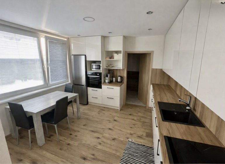 A kitchen in a 3-room apartment with a wooden decor floor and light furniture.