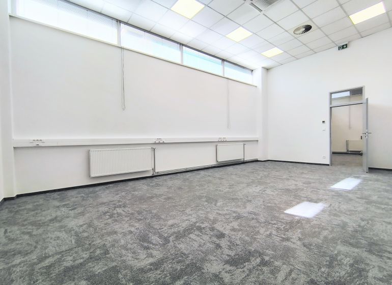 Bright commercial spaces with carpet and suspended ceiling, white walls, open doors.