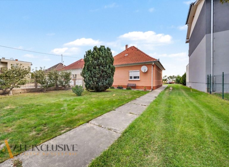 A family house in Povoda surrounded by lawn and trees, a concrete path leads to the house.