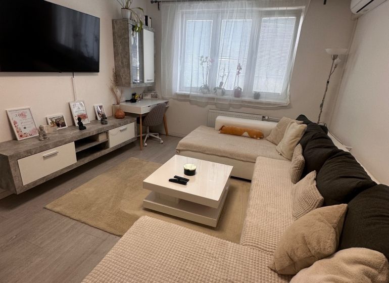 Living room in a 3-room apartment with a sofa, television, and table, floor with wooden decor.
