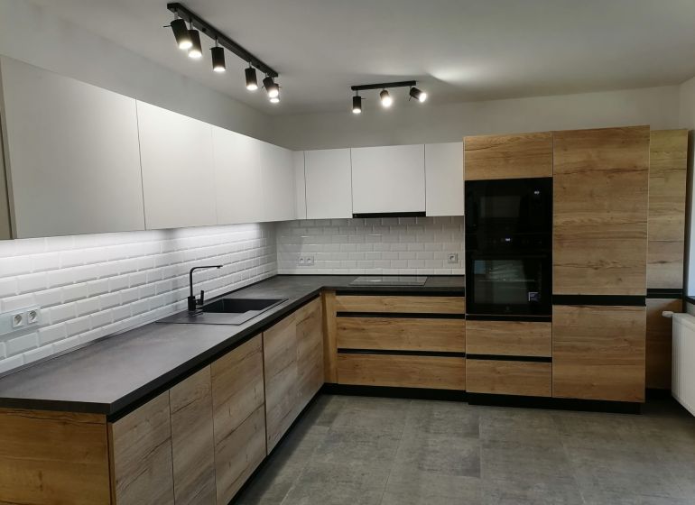 Modern kitchen in a 2-room apartment with white tiles and wood decor.