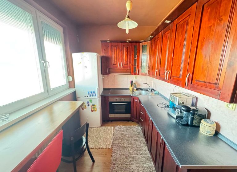 A kitchen with appliances and wooden decor in a 3-room apartment.