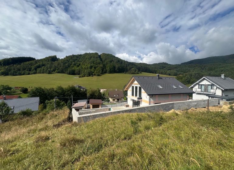 Residential plots in Považská Bystrica with a view of green hills and houses.