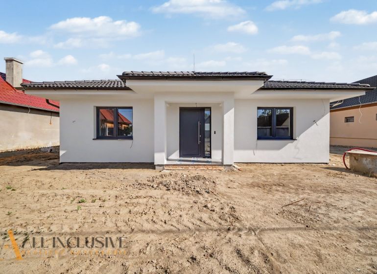 A family house in Tomášikovo with a white facade and a dark roof.