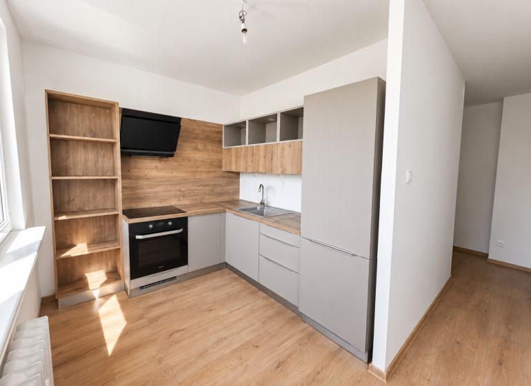 A kitchen in a 2-room apartment with a wooden decor floor and modern equipment.