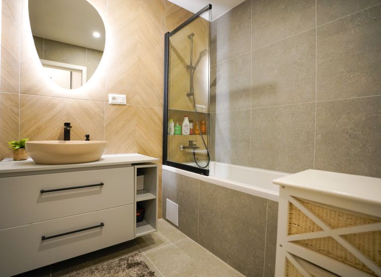 A bathroom with a bathtub and a mirror decorated with tiles in a 3-room apartment.