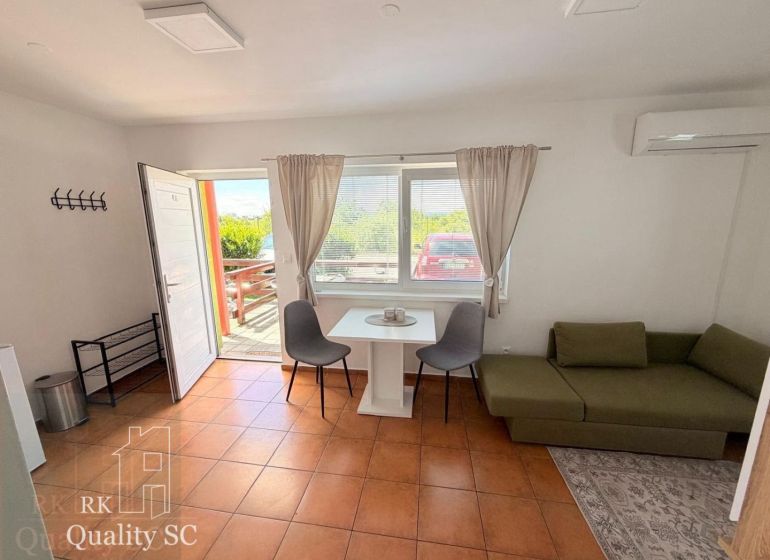 A studio apartment with a terracotta floor, a green sofa, and a table with chairs.