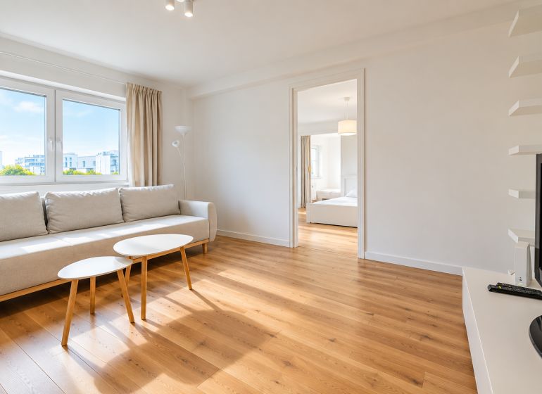 Living room in a 2-room apartment with a sofa, tables, and a floor with a wooden decor.