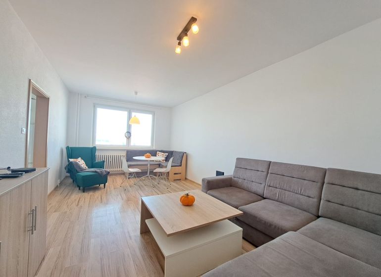 Living room in a three-room apartment with a wooden decor floor and a comfortable couch.