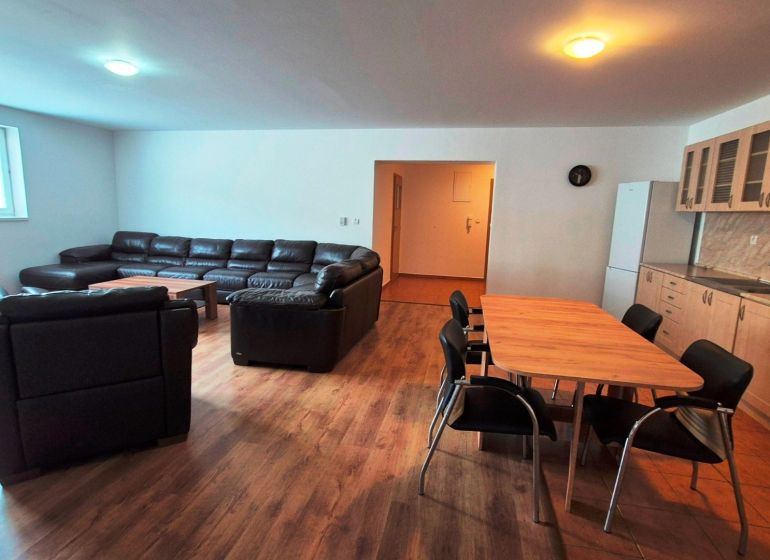 Living room with a sofa, dining table, and kitchen unit in a three-room apartment.