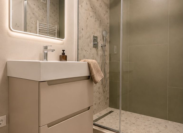 Bathroom with a sink, shower corner, and illuminated mirror in a 3-room apartment.