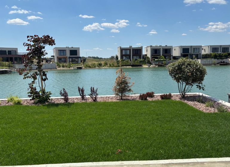 A family house in Boldog with a garden by the lake and a green lawn.