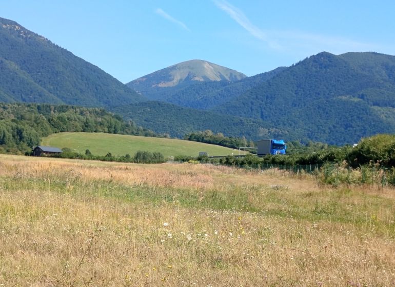 Recreational lands near the town of Turany with a mountain range and a truck on the road.