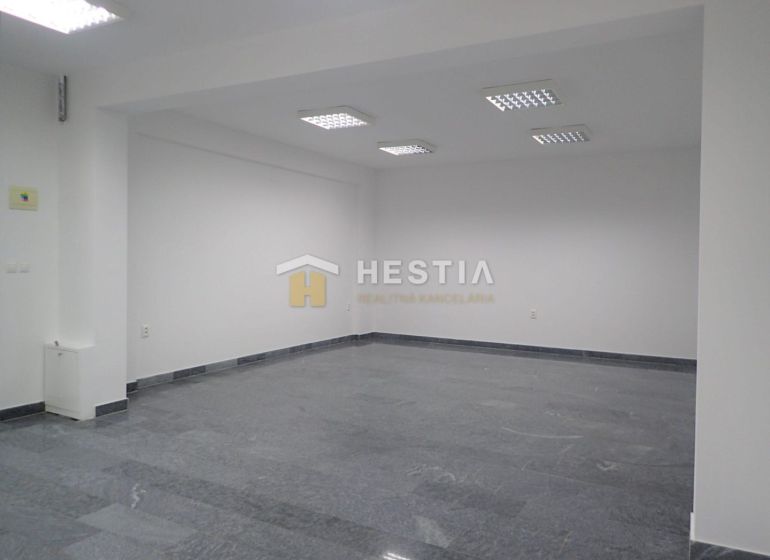 An empty commercial space with wood-patterned flooring and white walls.