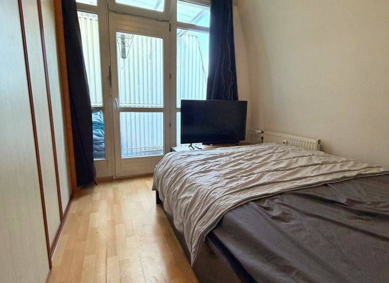 Bedroom in a 2-room apartment with a bed, wardrobe, and floor with wooden decor.