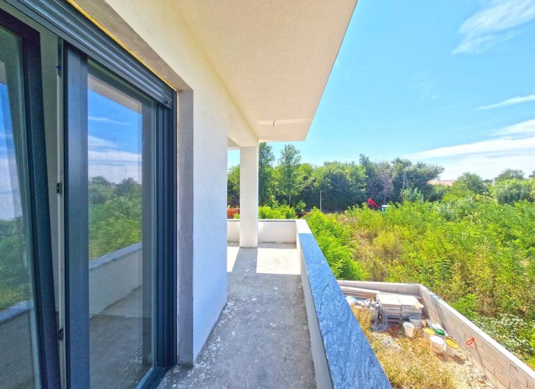 A balcony of a 3-room apartment in Privlaka with a view of greenery and blue sky.