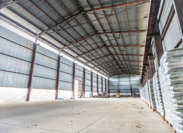 Warehouses and halls in Dulov with metal roofs and stored materials inside.