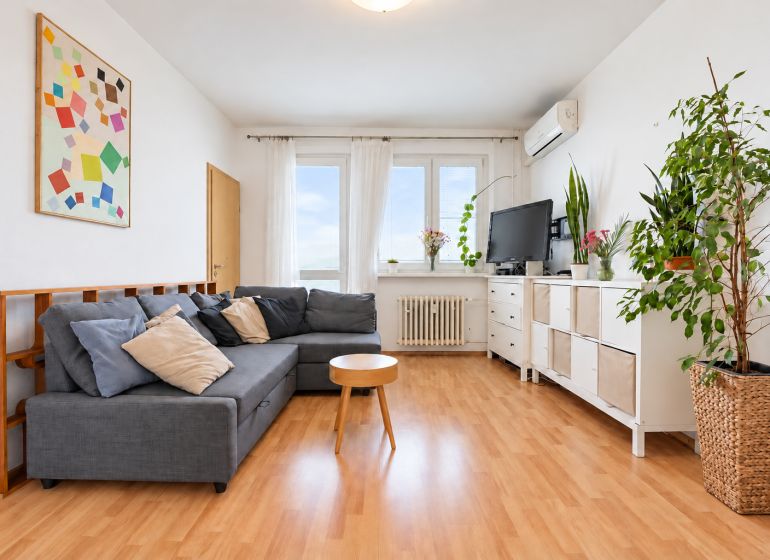 A living room in a 3-room apartment with a wooden decor floor and comfortable seating.