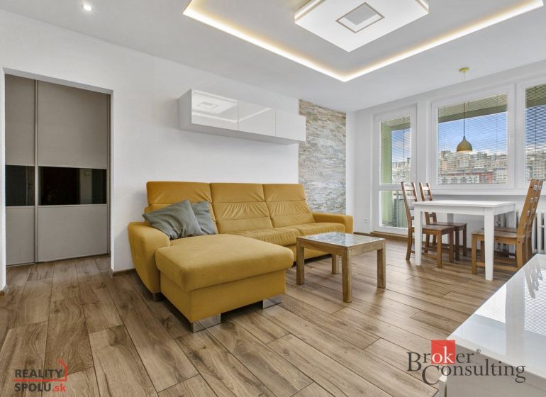A living room in a 5 or more room apartment with a wood-patterned floor and a yellow sofa.