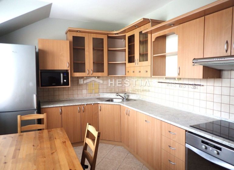 A kitchen in a 3-room apartment with wooden cabinets and a dining table.
