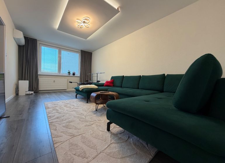 Living room in a three-room apartment with a wooden decor floor and a comfortable sofa.