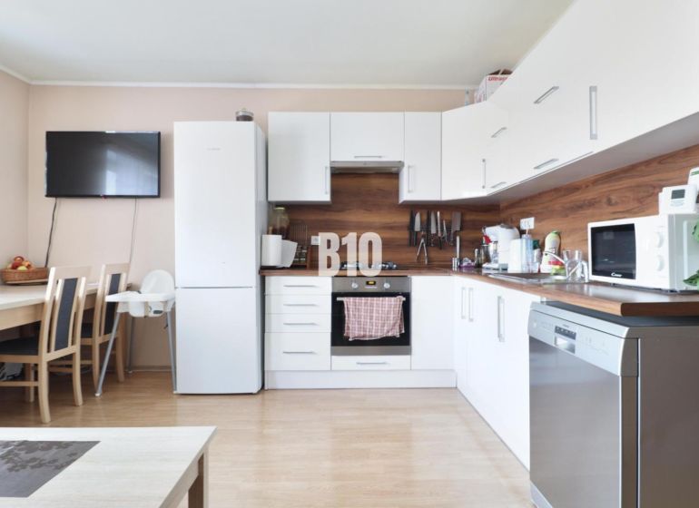 A kitchen in a 3-room apartment with white cabinets and a wooden decor floor.