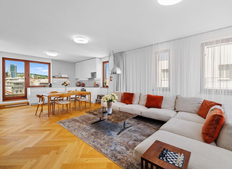 A spacious living room with a corner sofa, a dining table, and a wooden decor floor.