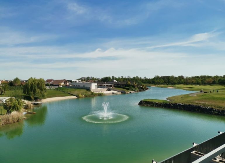 A view of the lake with a fountain and surrounding greenery on Golfová Street in Hrubá Borša.