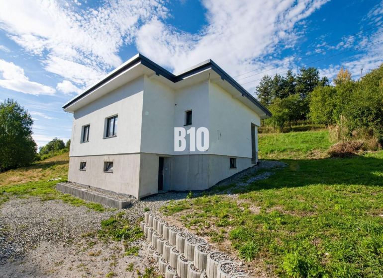 A family house in Skalité surrounded by greenery and a clear blue sky.