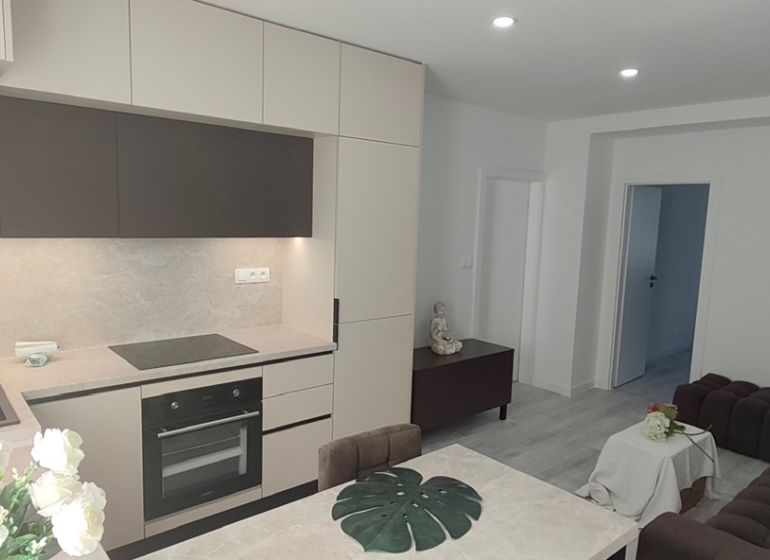 A kitchen in a 3-room apartment with a modern kitchen unit and wood decor.