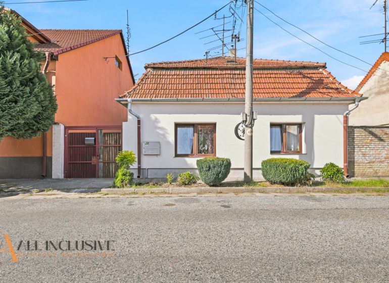 A family house in Komárno with a white facade, red roof, and well-maintained garden.