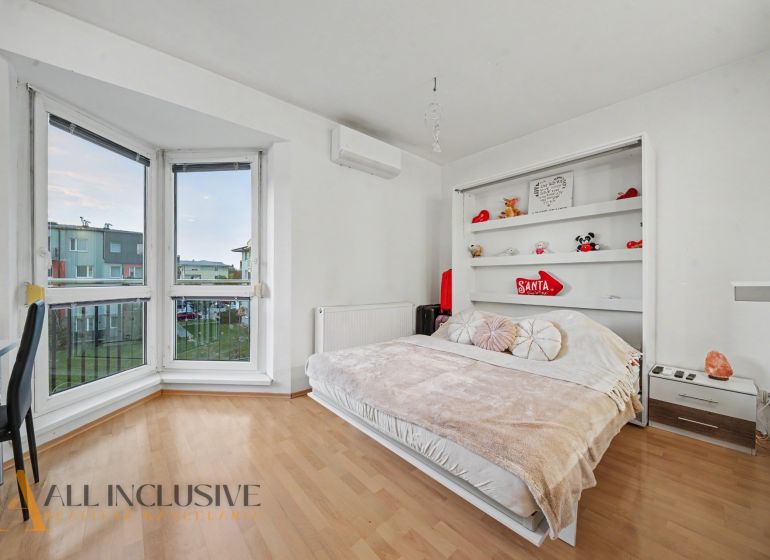 Interior of a 1-room apartment with a bed, shelf, and floor with wood decor.
