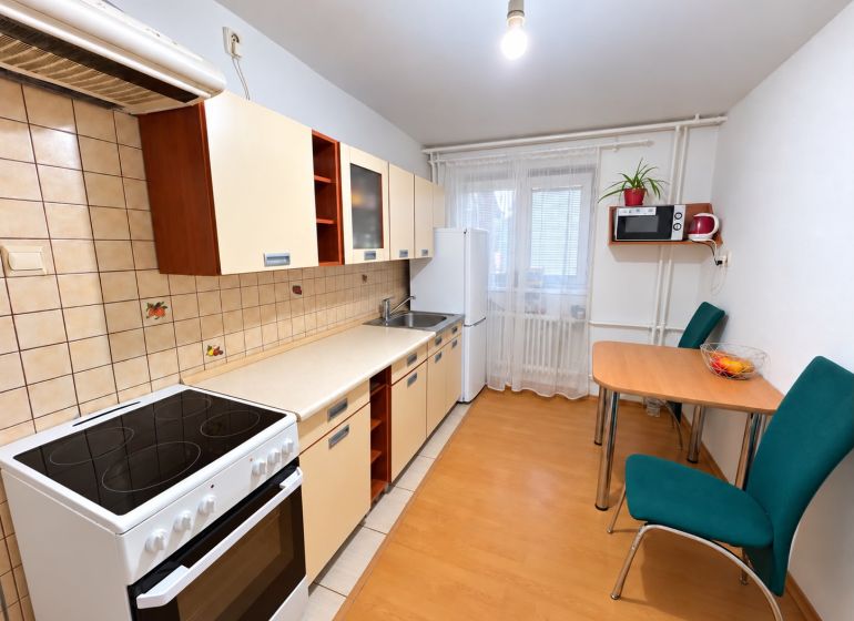 A kitchen in a one-room apartment with a wooden decor floor, dishes, and appliances.