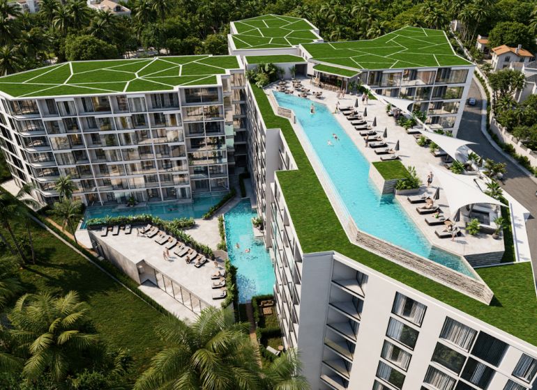 Apartment construction in Phuket with a rooftop pool surrounded by greenery.