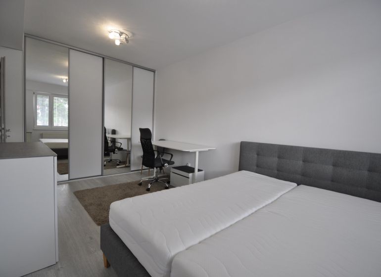 A bright bedroom with a work corner and built-in wardrobes in a 2-room apartment.