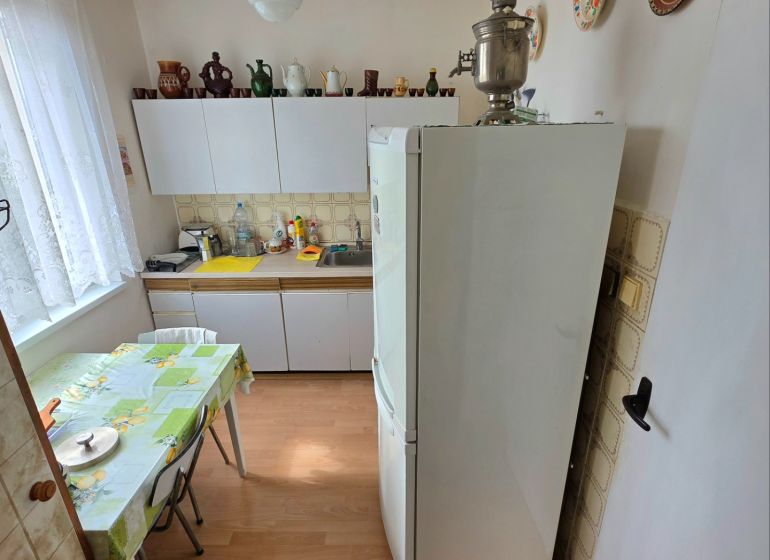 A kitchen in a 2-room apartment with a wooden decor floor and wall plates.