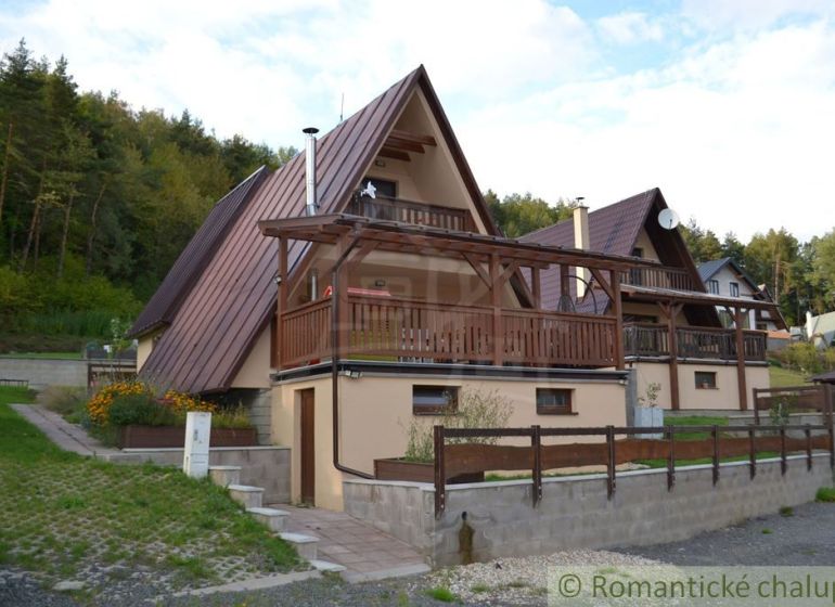 A cottage in Nižná Polianka with wooden details, surrounded by greenery and forest.