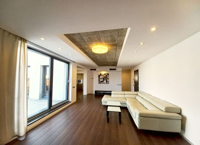 Living room in a 4-room apartment with a glass wall and wooden decor flooring.