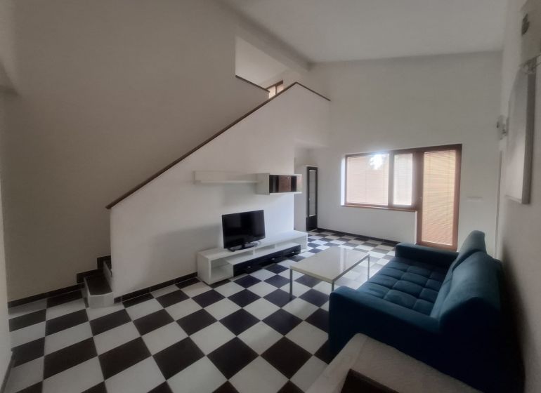 A living room in a family house with a blue sofa and black and white checkered floor.